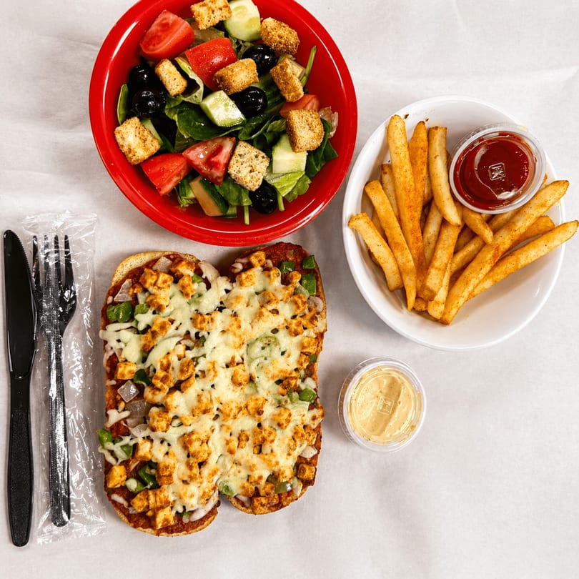 A chicken pizza bread, side salad, and french fries with ketchup and a dipping sauce.